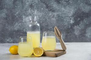 Cups full of lemonade with slice of lemon and wooden reamer photo
