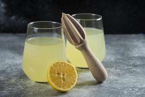 Cups of lemonade with slice of lemon and wooden reamer photo