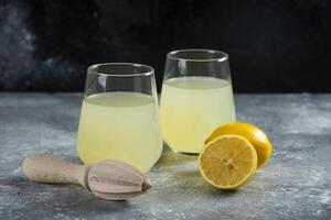 Cups of fresh lemonade with slice of lemon and wooden reamer photo