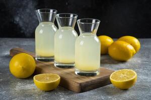 Three glass jugs of tasty lemonade on a wooden board photo