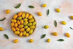 Top view, Pile of kumquats on wooden plate over colorful background photo