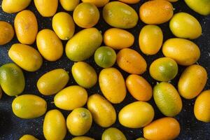 Top view. Pile of kumquats over blue background photo