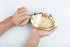 Man opening canned fish. White packed meat photo