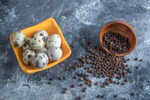 Bowl of quail eggs with black pepper seeds photo