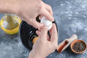 Making breakfast. Man breaking eggs in bowl photo