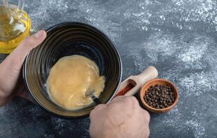 Man mixing egg in black bowl. Over grey background photo