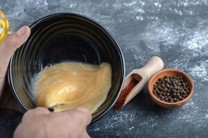 Man mixing egg in black bowl. photo