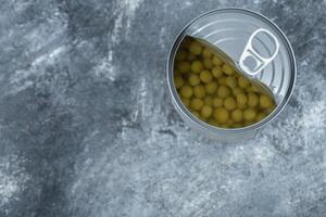 Top view of opened tin green olives on grey background photo