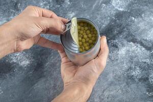Man trying to open tin. Green olives photo