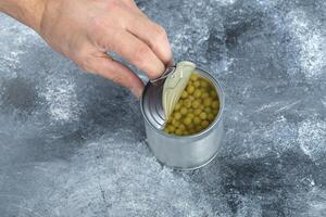 Close up photo of man opening tin olives