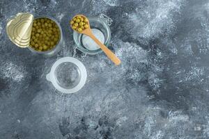 Top view of Opened olive tin with jar over grey background photo