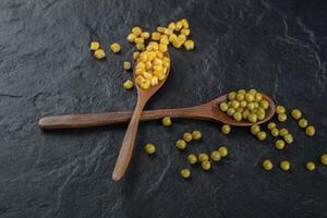 Two wooden spoon with canned corns and olives photo