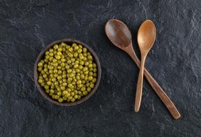 Two wooden spoon and bowl full with green marinated olive photo