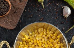 Metal bowl full with marinated corn seeds and spices on background photo