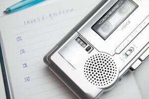 A tape recorder with buttons is on a notebook labeled investigation. the white background and workspace of the student detective professor. High quality photo