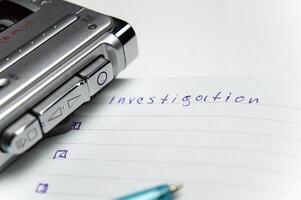 A tape recorder with buttons is on a notebook labeled investigation. the white background and workspace of the student detective professor. High quality photo