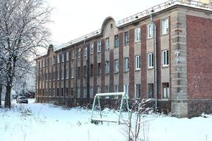 An Abandoned Building Surrounded by a Beautiful Winter Landscape in a Gloomy Setting photo