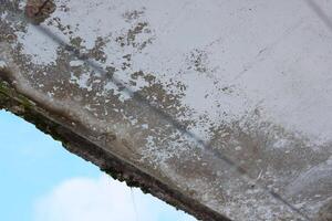 An aged, weathered concrete structure stands prominently against a clear blue sky above photo