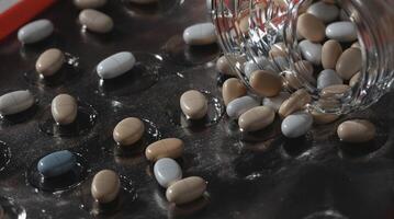 A beautiful array of colorful beans has spilled out from a jar onto a dark surface photo