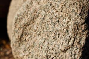 A closeup view of a rough stone surface illuminated by natural light, highlighting its texture photo