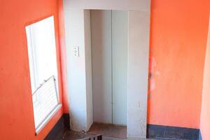 An Abandoned Elevator Located Within a Setting Composed of Distinct Orange Walls photo