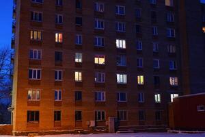 An Apartment Building Captured at Dusk, Featuring Beautifully Illuminated Windows and Scenes photo