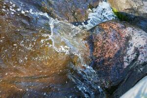 The captivating sight of flowing water gracefully cascading over rocks in a natural stream photo