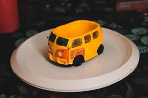 A Delightful and Colorful Yellow Bus Figurine Displayed Beautifully on a Decorative Plate photo