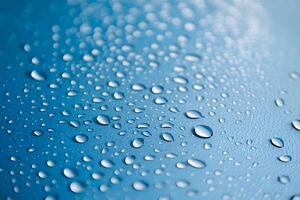 Glistening water droplets on blue surface create sparkling, gradient visual effect photo