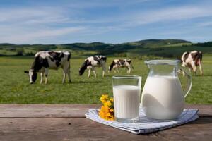 Rustic table with milk pitcher, checkered cloth, and grazing cows in meadow photo