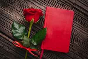Red rose with notebook on rustic wooden background creates romantic elegance photo