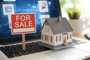 Mini house on laptop keyboard beside For Sale sign in digital setting photo