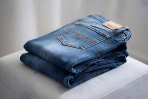 Folded blue jeans on surface with sharp stitching details in blurred background photo