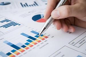 Hand poised with silver pen on a colorful bar chart symbolizes data analysis photo