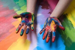 Hands covered in colorful paint rest on painted canvas, exuding creativity photo