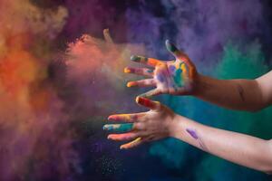 Hands smeared with colorful paint against multicolored cosmic background photo