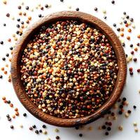 Mix of quinoa seeds in wooden bowl on white background, top view photo