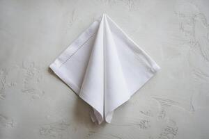 Folded white napkin, triangular shape, textured gray background adds elegant simplicity photo