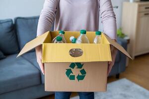 Cardboard bin with recycling symbol, bottles inside, indoor focus on sustainability photo