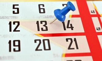 A calendar with a blue push pin on the top photo
