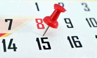A red pin is stuck into the calendar photo
