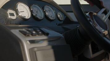 Close-up view of a modern yacht dashboard, featuring gauges, buttons, and a steering wheel. The scene captures the precision and functionality of marine navigation equipment in natural light video