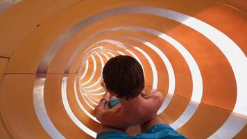 Young boy enjoying the thrill of twisting down a vibrant water slide, filled with excitement and joy on a sunny day video