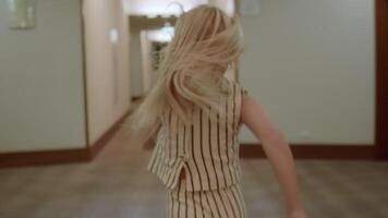 Young girl with long hair joyfully running through a hotel hallway, creating a sense of adventure and wonder in a modern indoor setting video
