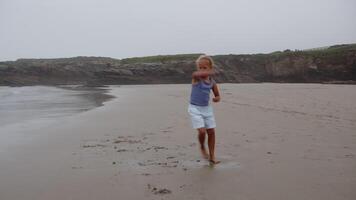 Young girl practicing karate moves on a sandy beach, surrounded by cliffs and the ocean in the background video