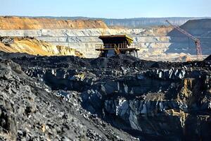 Open-Pit Mining. Excavating Coal Resources with Heavy Machinery in a Vast Quarry, Daytime Sunlight Illuminating the Landscape. Industrial Extraction of Fossil Fuels and Environmental Impact Assessment photo