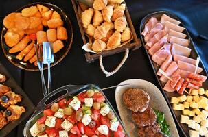 A buffet of food on a table with trays of meat, cheese and vegetables photo