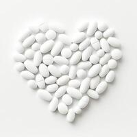 White pills arranged in a heart shape on a plain background symbolizing health and wellness photo