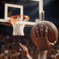 Hand of a player preparing to shoot a basketball during a competitive game in a crowded arena at night photo