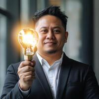 Business professional holds light bulb symbolizing innovation in modern office setting photo